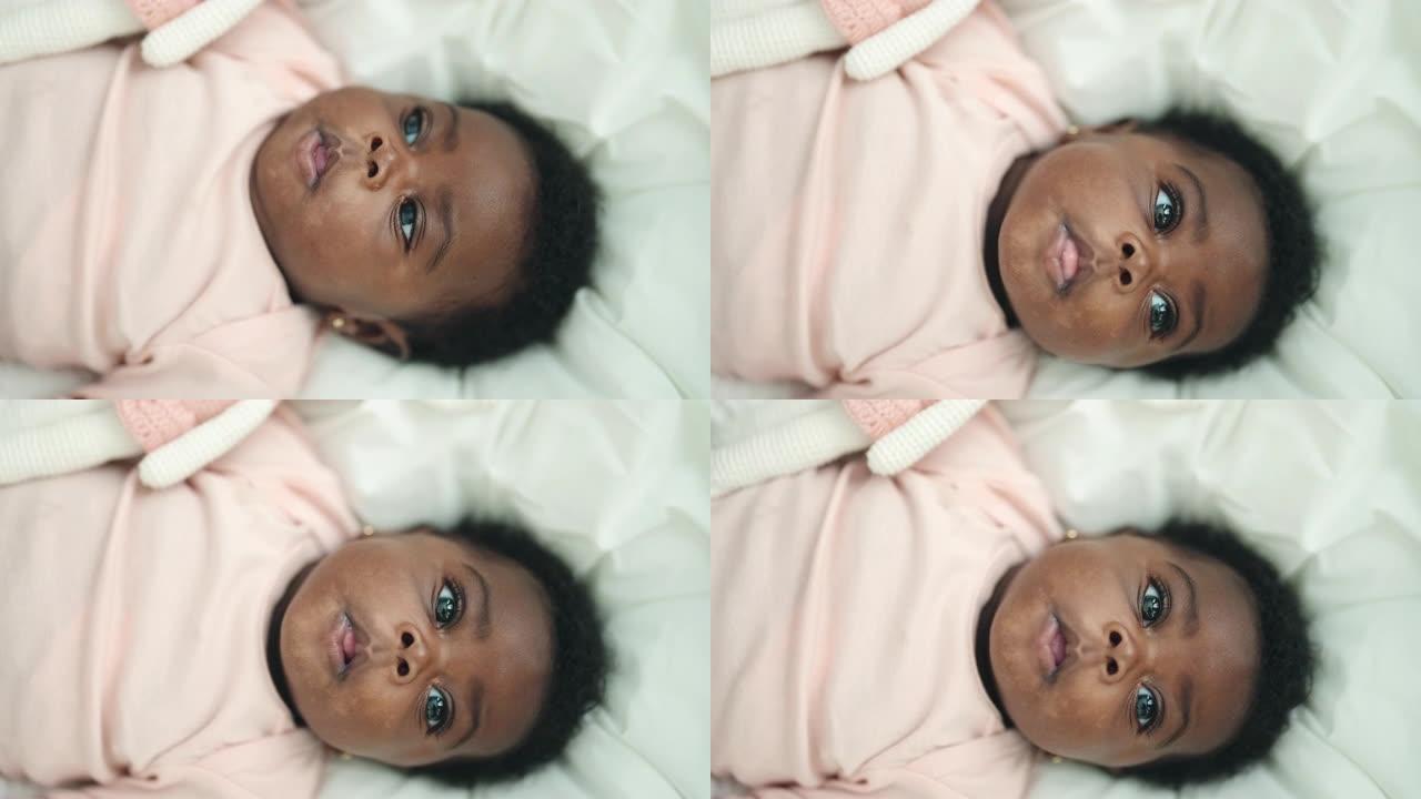 非裔美国人婴儿躺在床上，在卧室里表情轻松