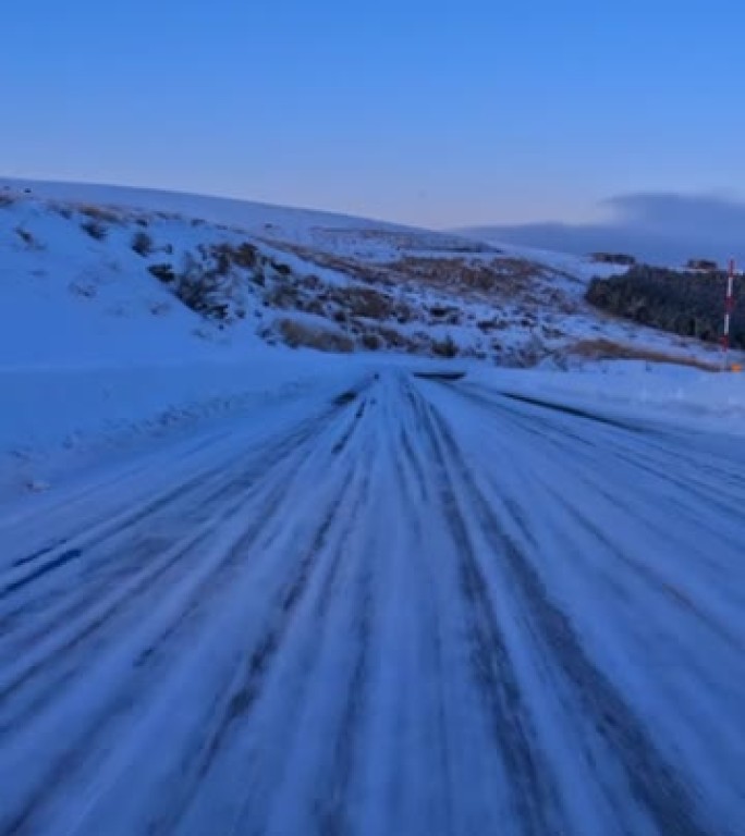 黄昏时在雪山路上行驶。