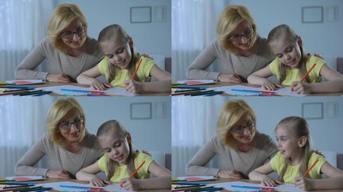 有爱心的退休妇女看着可爱的孙女用彩色铅笔绘画