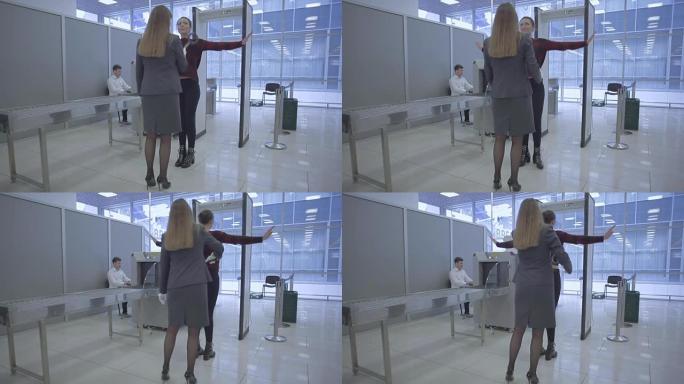 机场工作人员在机场用手扫描仪扫描一名女性的身体