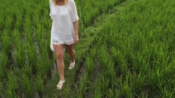 女人在草地护堤上穿越稻田