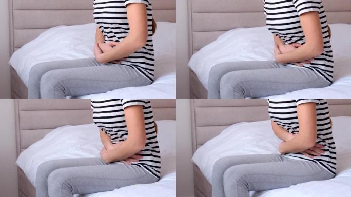 一个女人坐在床上，在月经周期中腹痛的特写镜头