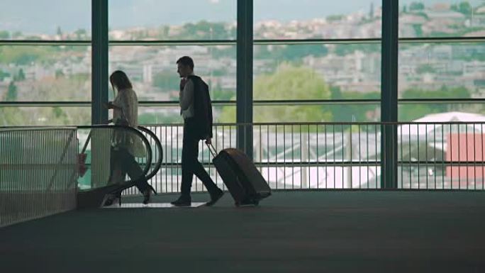 出差，男女步行到机场自动扶梯，提着行李