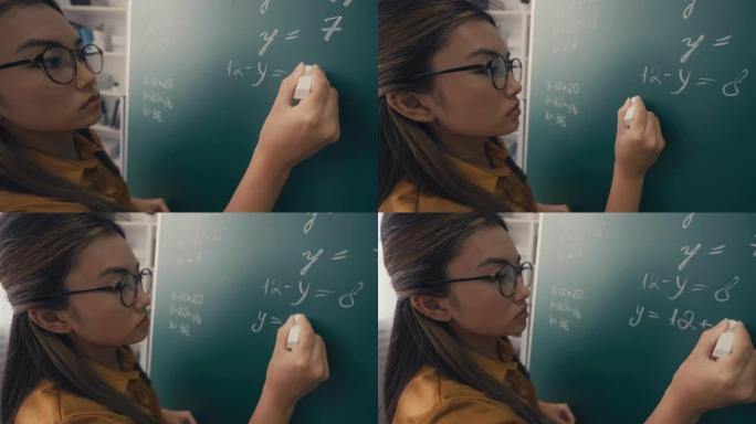 专注的亚洲女教师在课堂上写方程式的特写