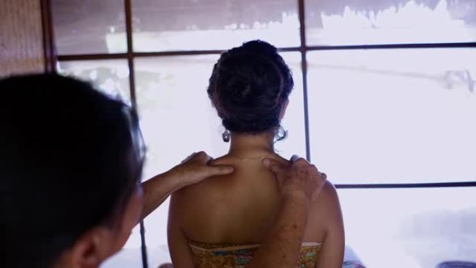 年轻女性在泰国美容水疗中心接受按摩的后视图