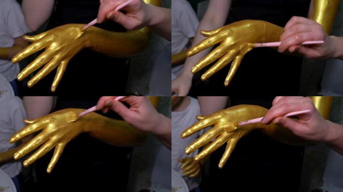 模特女孩用金色颜料画她的手。
