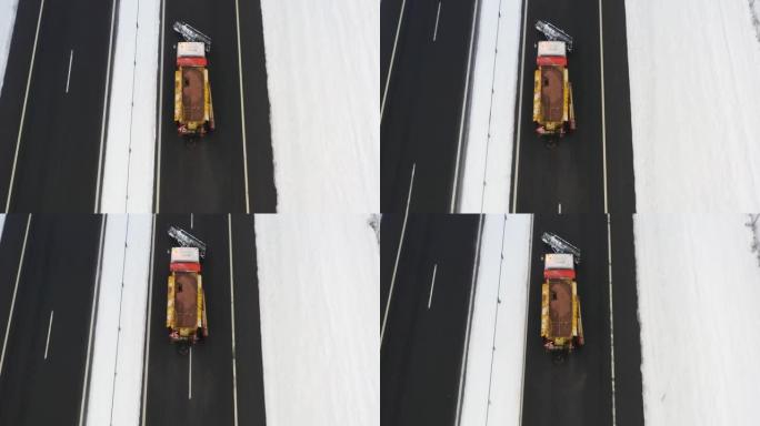 扫雪车沿着高速公路行驶，并在道路上撒盐和试剂