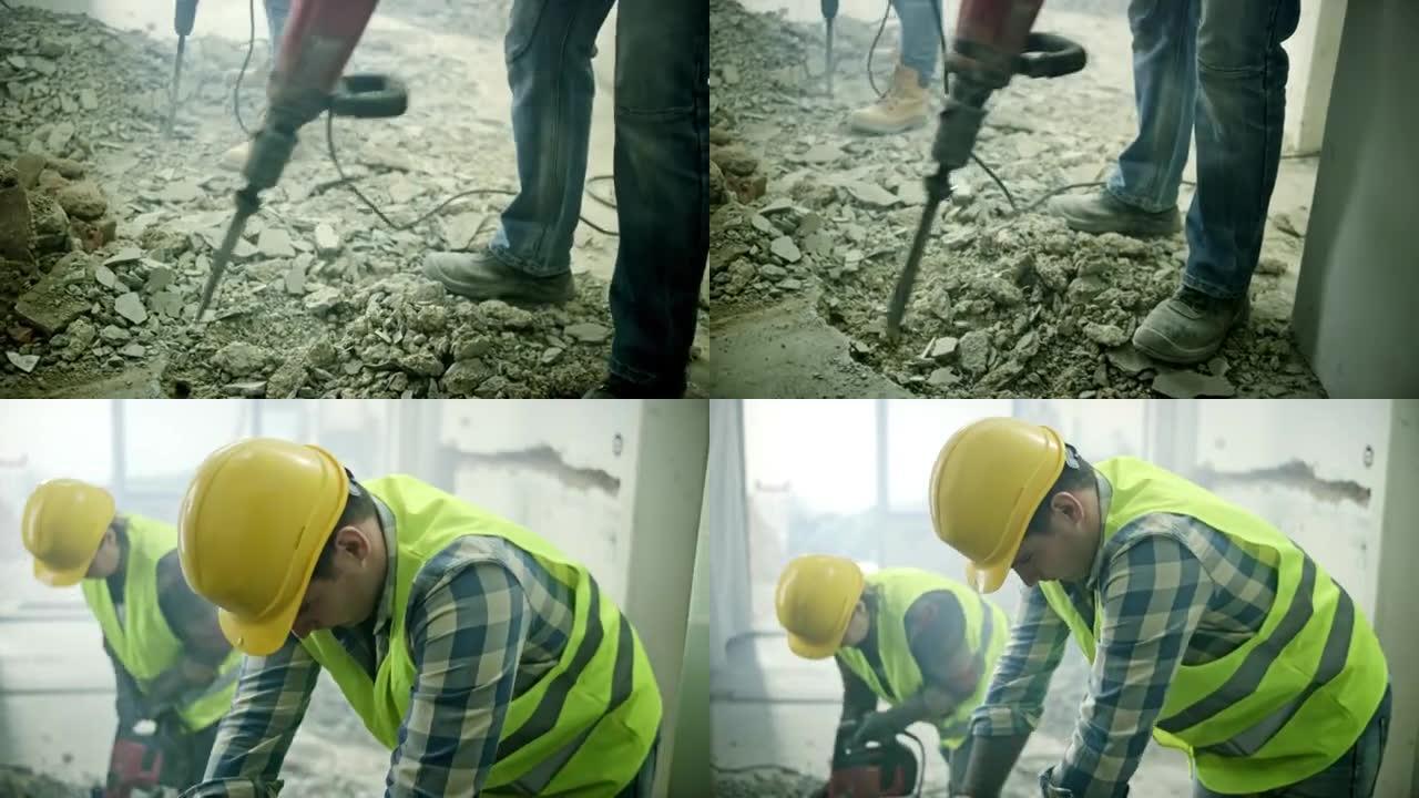 两名工人用手提凿岩机将混凝土地板打碎。