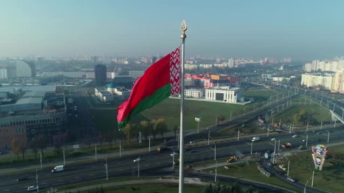 在一个阳光明媚的早晨，白俄罗斯国旗飘扬在蓝天和明斯克的城市景观上