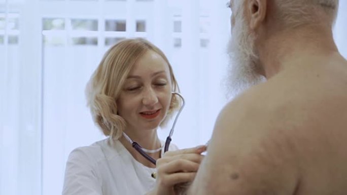 微笑的医生用听诊器听老人的心脏