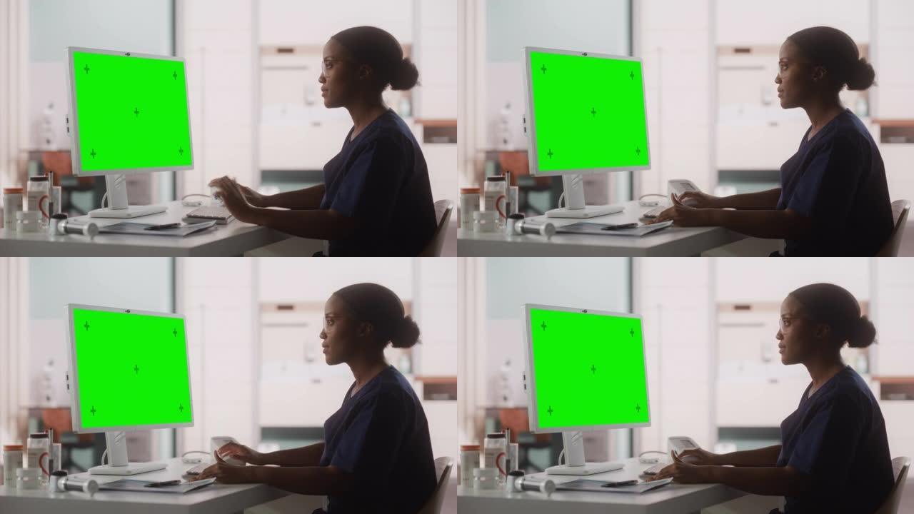 一名黑人女性医疗保健专业人员的肖像在医院办公室的台式电脑上工作，绿屏模拟显示。诊所护士长正在在线指定