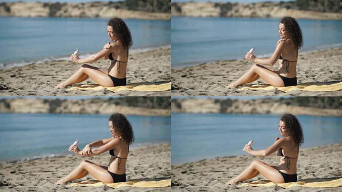 年轻女孩在海滩上的手上涂抹防晒霜