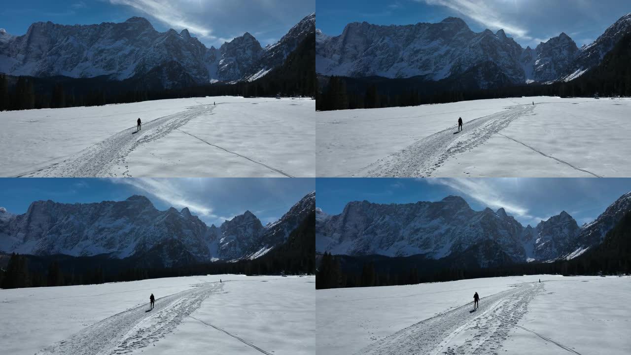 空中无人机拍摄的一名妇女在山区附近的雪地中徒步旅行