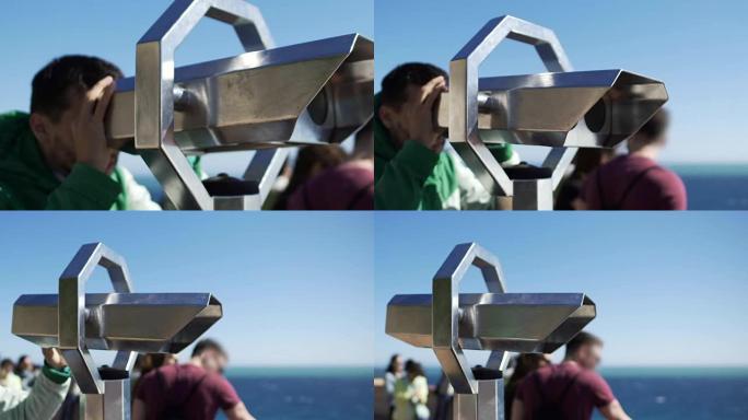 男性游客在观光平台上通过双筒望远镜观察城市景观