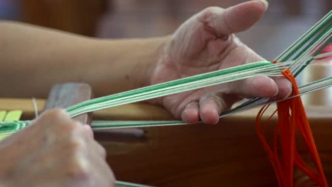 手指将绿色和白色的琴弦分开，并用木棍将它们编织在一起，以慢动作拍摄为特写镜头
