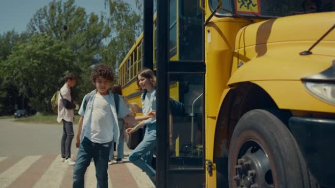 两个小学生走出校车。青少年站在公共汽车上聊天。