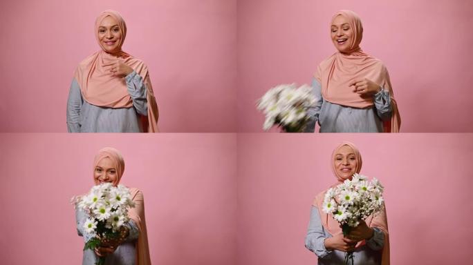 一位迷人的中东穆斯林妇女戴着粉红色的头巾，微笑着，手里拿着一束可爱的花