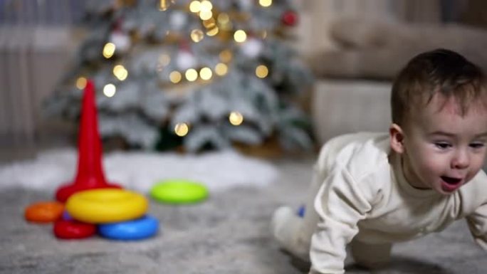 可爱的高加索孩子玩玩具金字塔。男婴扔玩具上衣，跟着拿。背景下的圣诞树。