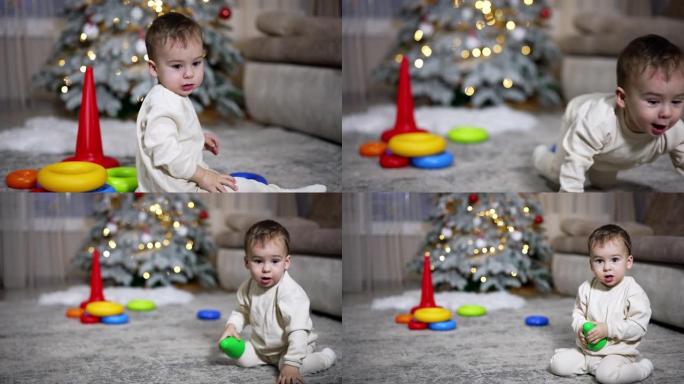 可爱的高加索孩子玩玩具金字塔。男婴扔玩具上衣，跟着拿。背景下的圣诞树。