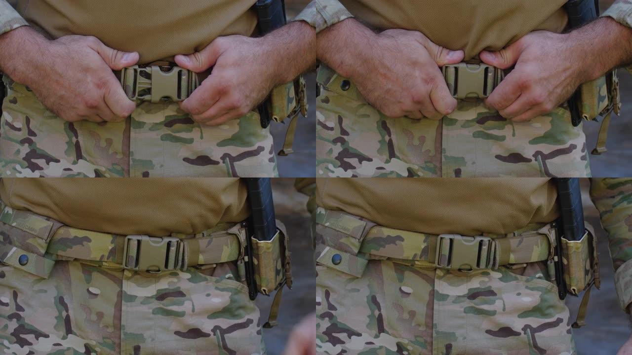 一名穿着迷彩服的难以辨认的男性士兵准备进行军事演习或战斗的手部特写。一个军人正在系腰带。乌俄战争