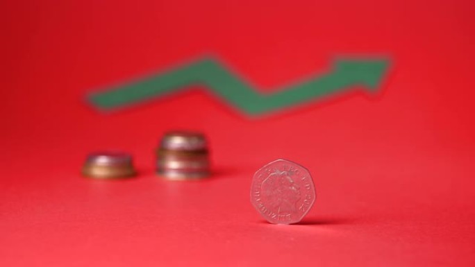 英国货币 -- 红色背景下的五十便士。背景中模糊的生长迹象。为未来省钱。