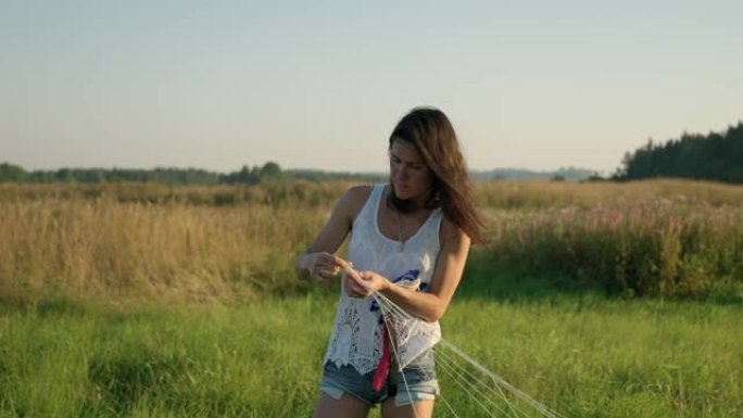 在炎热的夏日，一个年轻的女孩解开风筝上的线条。手的特写。