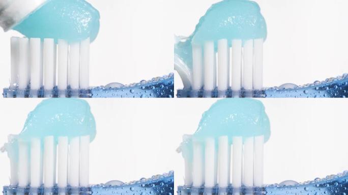 牙刷和牙膏。在蓝色牙刷上慢慢挤压白色背景上的蓝色牙膏。宏视图和慢动作视图
