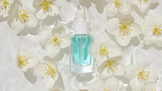 化妆品瓶，小瓶和茉莉花花瓣在水面上滴落。反射阳光和阴影的纯净水。波浪水的慢动作。设计、广告、产品