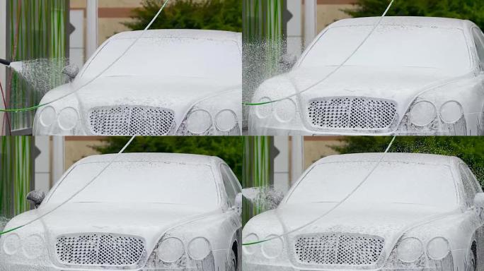 男人用泡沫物质喷洒昂贵的精英汽车，洗车业务