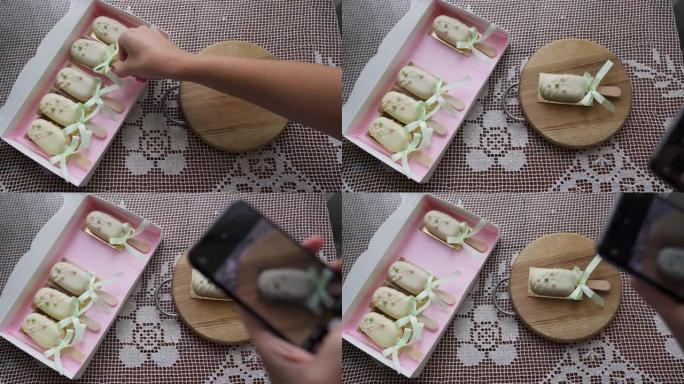 女人的特写镜头拿着智能手机拍摄甜品芝士蛋糕的照片。