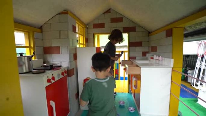 可爱的小男孩在玩耍时在幼儿园的假装厨房里玩耍