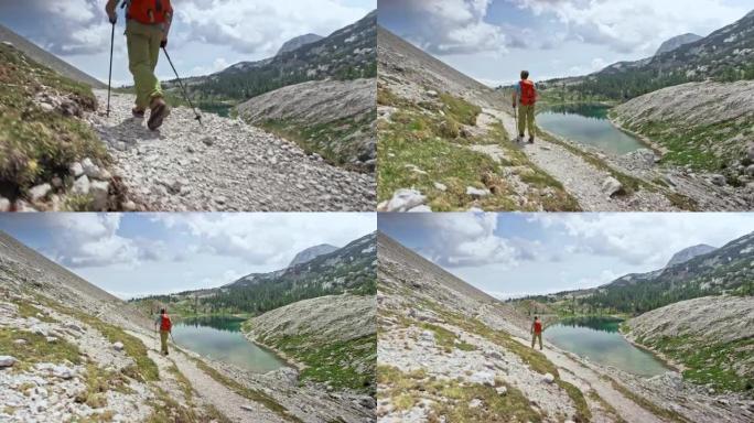 男性徒步旅行者在阳光下的山湖上方的砾石小径上行走