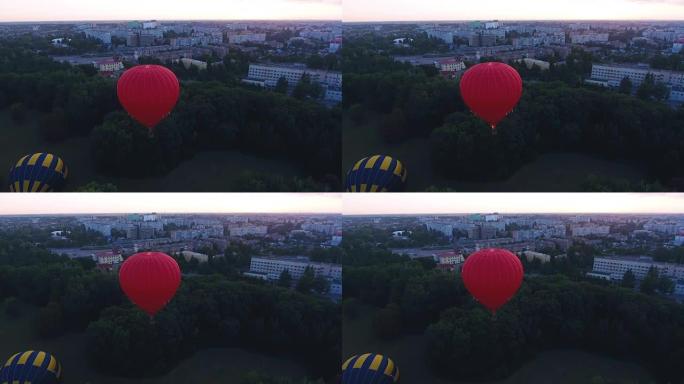 黎明时分，红色热气球漂浮在城市绿地上，节日提前飞行