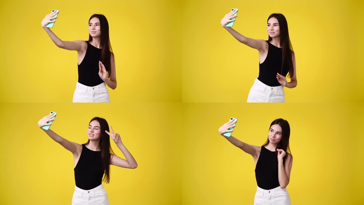 4k视频，可爱的女孩使用手机，在黄色背景上挥手打招呼。
