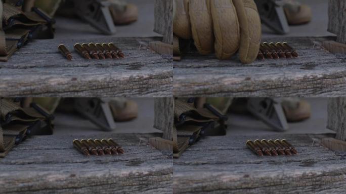 极端近距离的机枪子弹躺在一排在木头表面。一个戴着战术手套的人手抓住他们并向他们发起攻击。乌克兰军队，