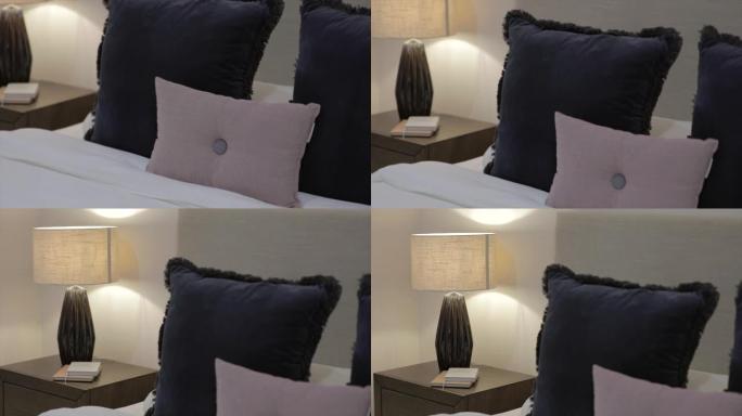 为商务旅客提供光线昏暗的酒店房间，柔软舒适的床上配有简单的靠垫。