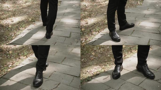 穿着黑色裤子和鞋子的商人沿着阳光明媚的小路走着，特写镜头。
