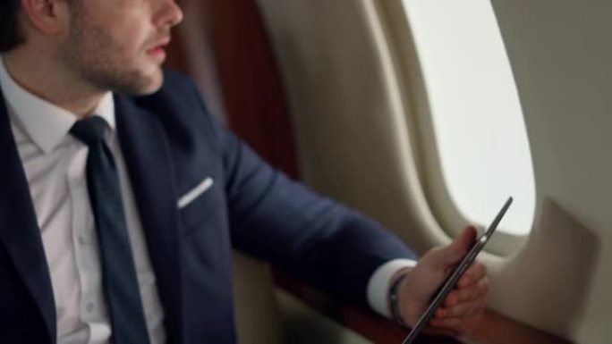 自信的领导者在飞机旅行中使用平板电脑。特写男士手触摸屏