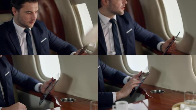 自信的领导者在飞机旅行中使用平板电脑。特写男士手触摸屏