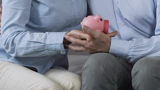 已婚夫妇手握存钱罐，适当的家庭预算计划