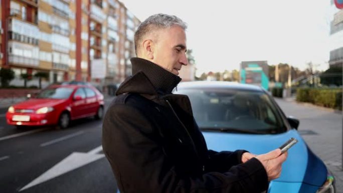满头白发的成熟男人在城市里给电动车充电