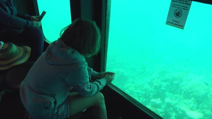 短发女孩正透过潜水艇上的水下窗户看