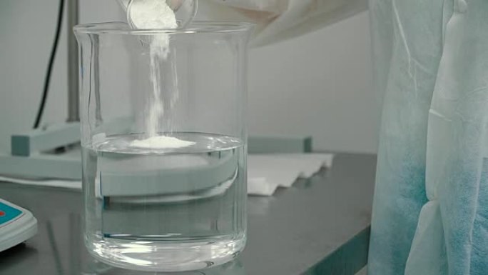 化学家将白色粉末放入带有液体的量杯中