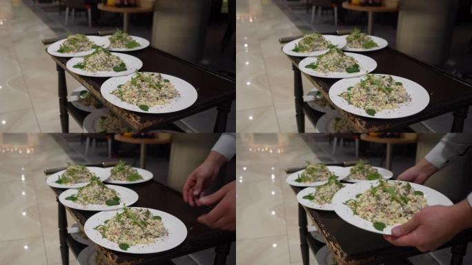 无法辨认的男服务员从餐厅的手推车上从厨房里拿出一盘熟食的特写镜头。