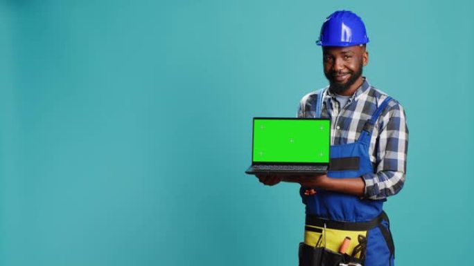 微笑的工匠展示带有绿色屏幕的笔记本电脑