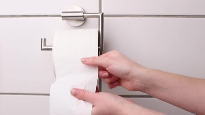女人撕下支架上的卫生纸。白纸，用品，厕所。痔疮，肠道问题。腹泻，大便问题