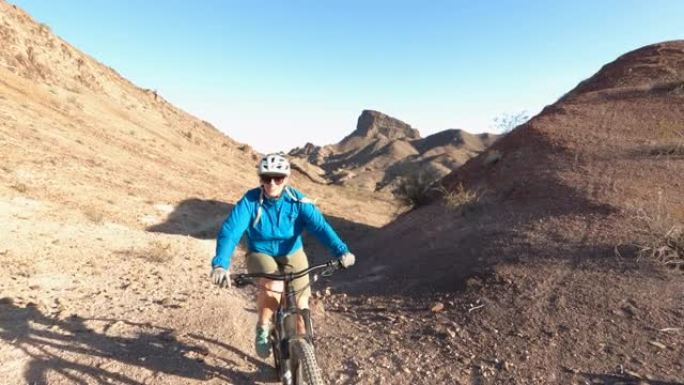 成熟女子骑着电动自行车在沙漠小径上行进，互相击掌