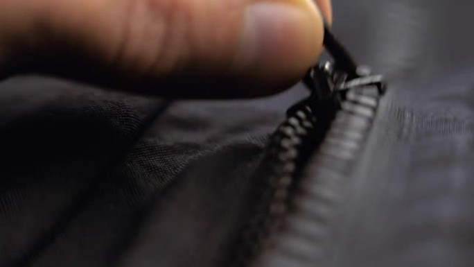 手解开拉链，将黑色塑料拉链系在衣服上。宏