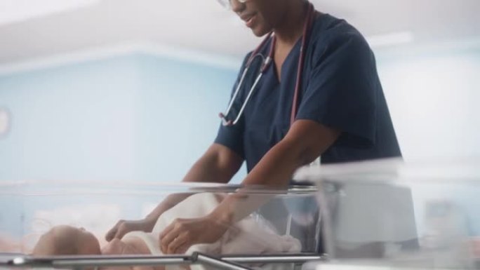 可爱的高加索新生婴儿躺在产科医院的摇篮里。美丽的黑色儿科医生用毯子覆盖孩子。医疗保健、怀孕和孕产概念