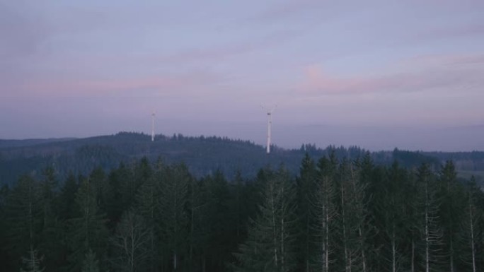 从远处看风力涡轮机的视野，森林在前面